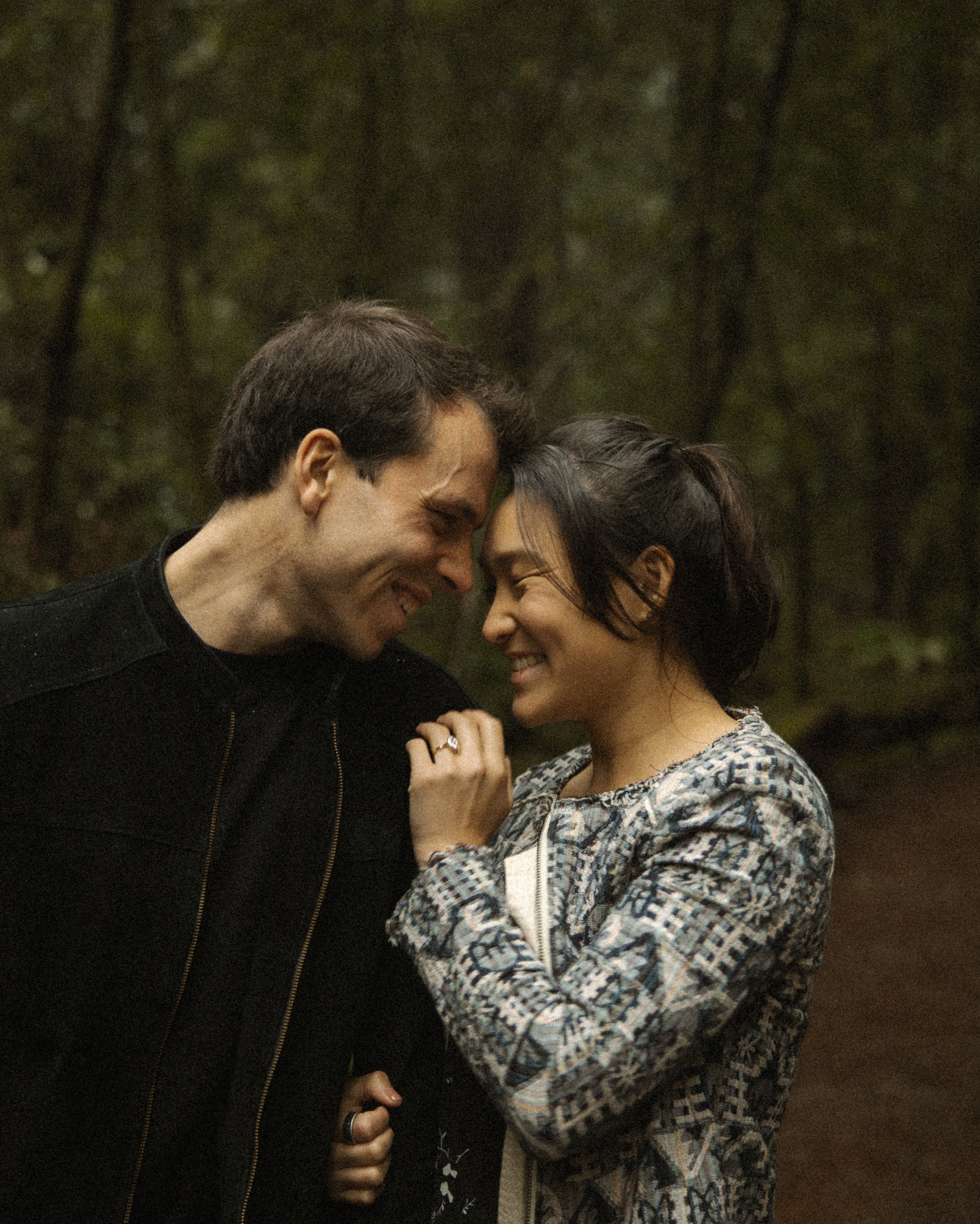 Laura and Eric, foreheads together in the forest